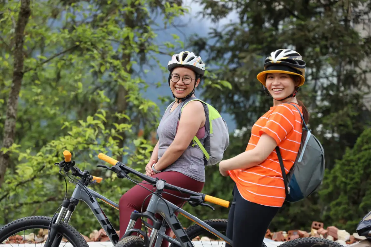 Two women cyclists posing with their bicycles in the green countryside of Ha Giang, Vietnam